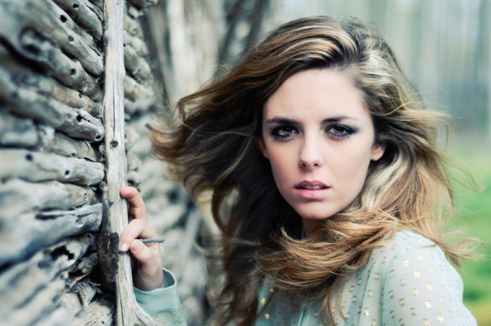 Beautiful blonde woman standing by a old wall